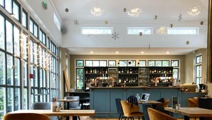 A spacious bar area with a wooden floor, bar stools, and a counter with a variety of bottles and glasses. - The Eagle House Hotel (Launceston)