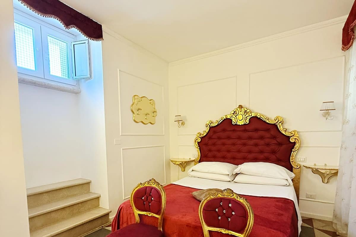 Une chambre avec un grand lit, deux chaises, un escalier et une fenêtre.