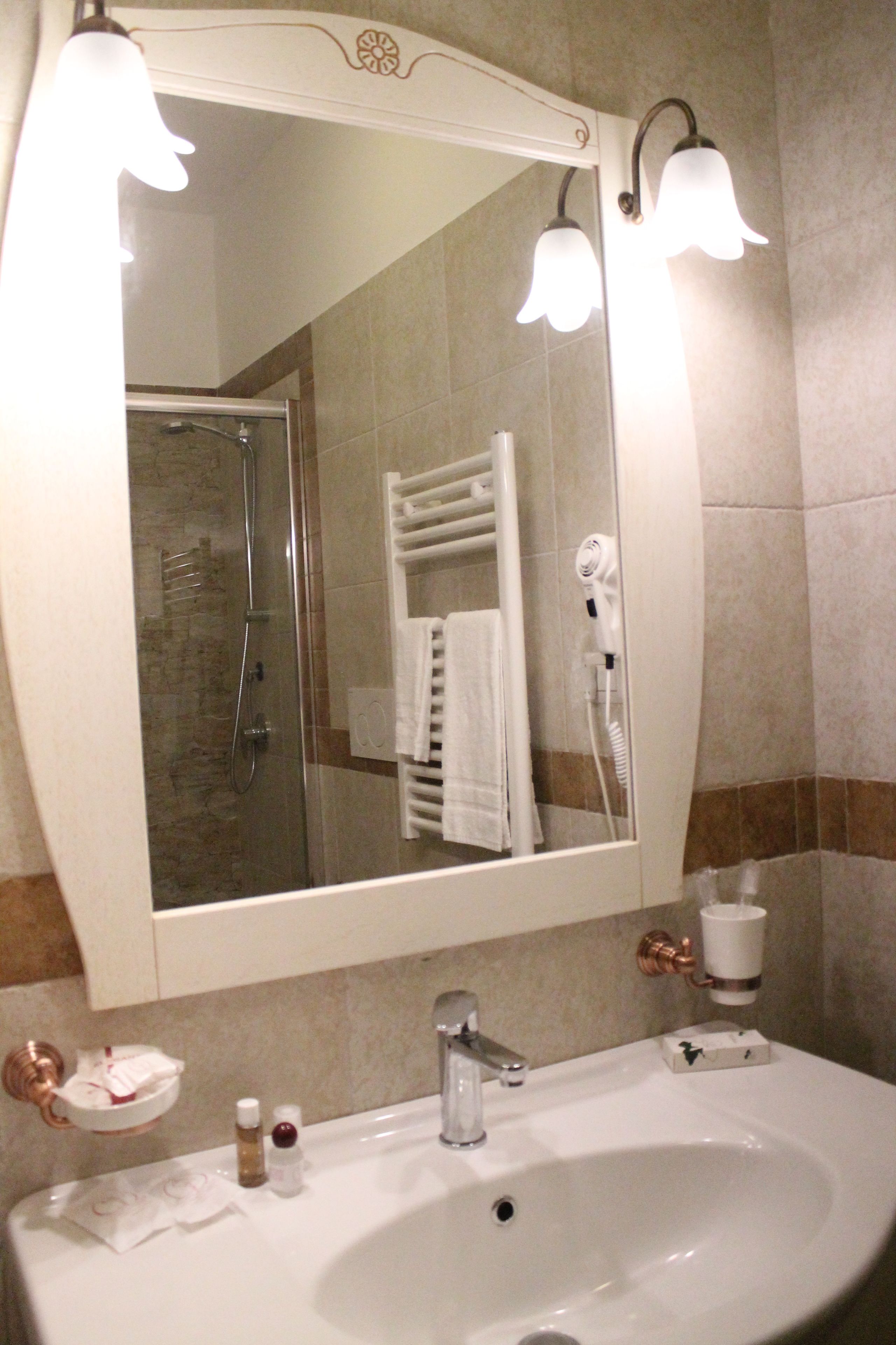 A bathroom with a large mirror, a sink, a towel rack, and a shower.