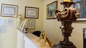 Un mostrador de recepción con una lámpara decorativa, diplomas enmarcados en la pared y un cuadro.