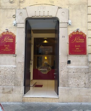 A hotel entrance with a red sign reading "Donna Bucrezia B&B" and a phone number.