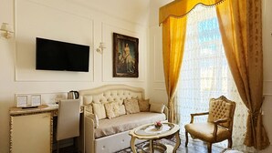 Una sala de estar con sofá, sillón, mesa de centro, televisor y piso estampado.