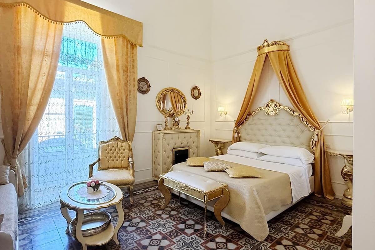 Une chambre avec un grand lit, une petite table ronde, une chaise et une table de chevet.