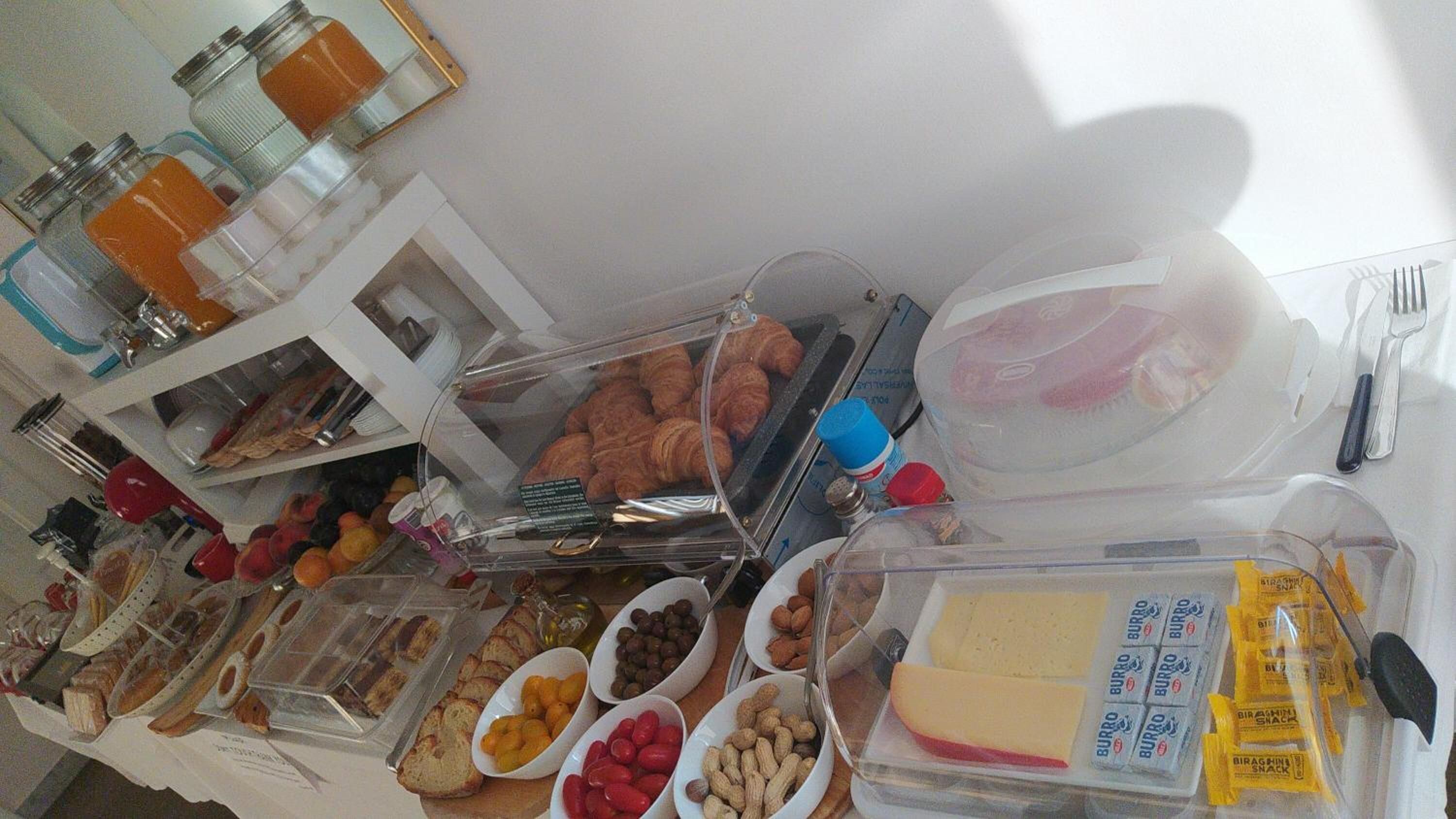 Una mesa de buffet con diferentes opciones de comida, incluyendo pasteles, frutas, frutos secos y queso.