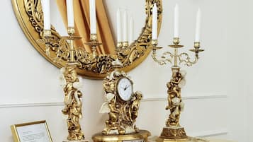 Un tocador lujoso con espejo de marco dorado, candelabros ornamentales y un reloj.
