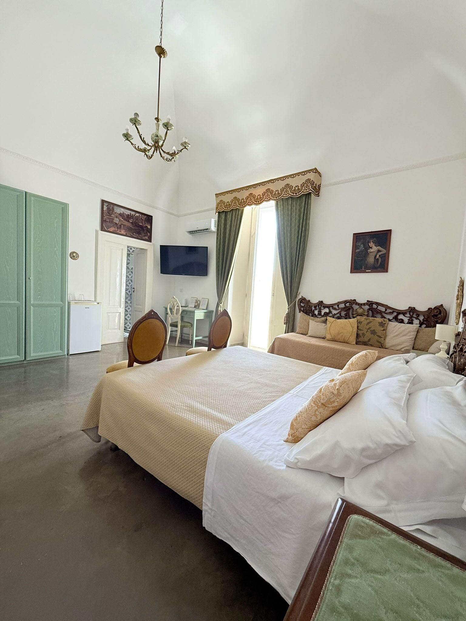 Quarto com cama grande, escrivaninha e televisão.