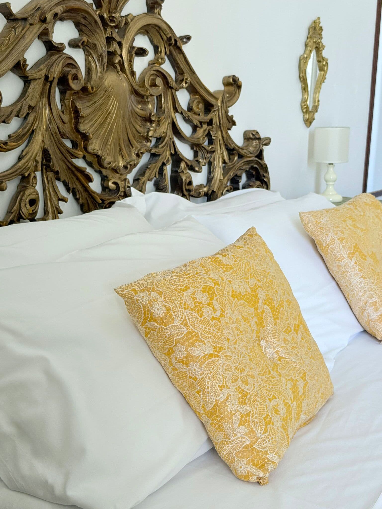 A bed with ornate headboard and two decorative pillows.