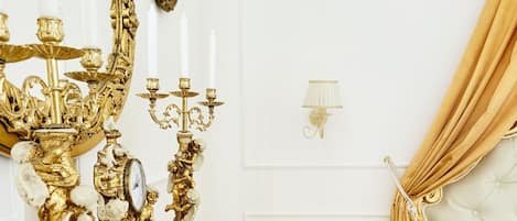 A luxurious bedroom with ornate gold furniture, a large mirror, and a bed with a golden drape.