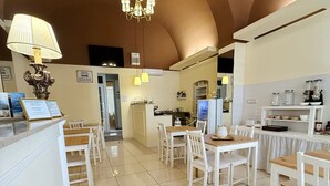Una cocina amplia con armarios blancos, una araña y un comedor con sillas blancas.