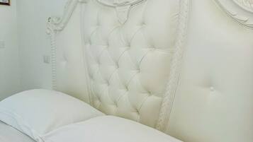 Una cama con cabecera capitonada y un único cojín blanco.