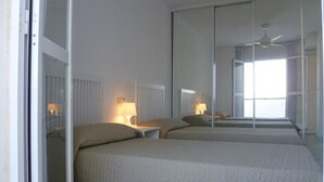 A hotel room with two beds, a large mirror, and a ceiling fan. - Duplex Penthouse Lunamar (Marbella)