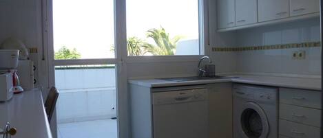 A compact kitchen with a washing machine, a dishwasher, and a sink.