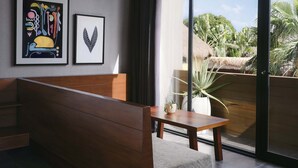 Una habitación moderna con un banco de madera, una mesita pequeña y dos cuadros enmarcados en la pared.