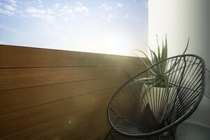 Una pared de madera y una silla de alambre negra cerca de una planta en maceta.