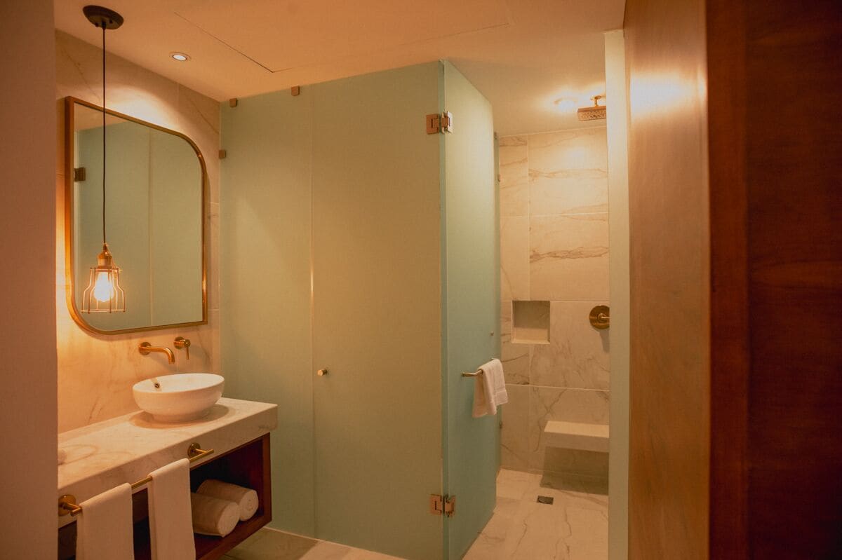 Un bany amb un lavabo blanc, un mirall amb marc daurat i un penjador de tovalloles.