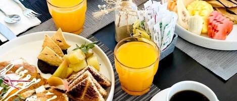 A breakfast buffet with various dishes, drinks, and utensils on a table.