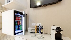 A modern kitchen with a built-in refrigerator, a coffee machine, and a flat-screen TV mounted on the wall. - Dolce Luxury Rooms (Rome)