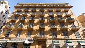 A multi-story building with balconies, a ground-floor shop, and a clear blue sky. - Dolce Luxury Rooms (Rome)