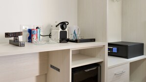 A hotel room with a white desk, a coffee machine, a Nespresso machine, a microwave, and a small refrigerator. - Dolce Luxury Rooms (Rome)