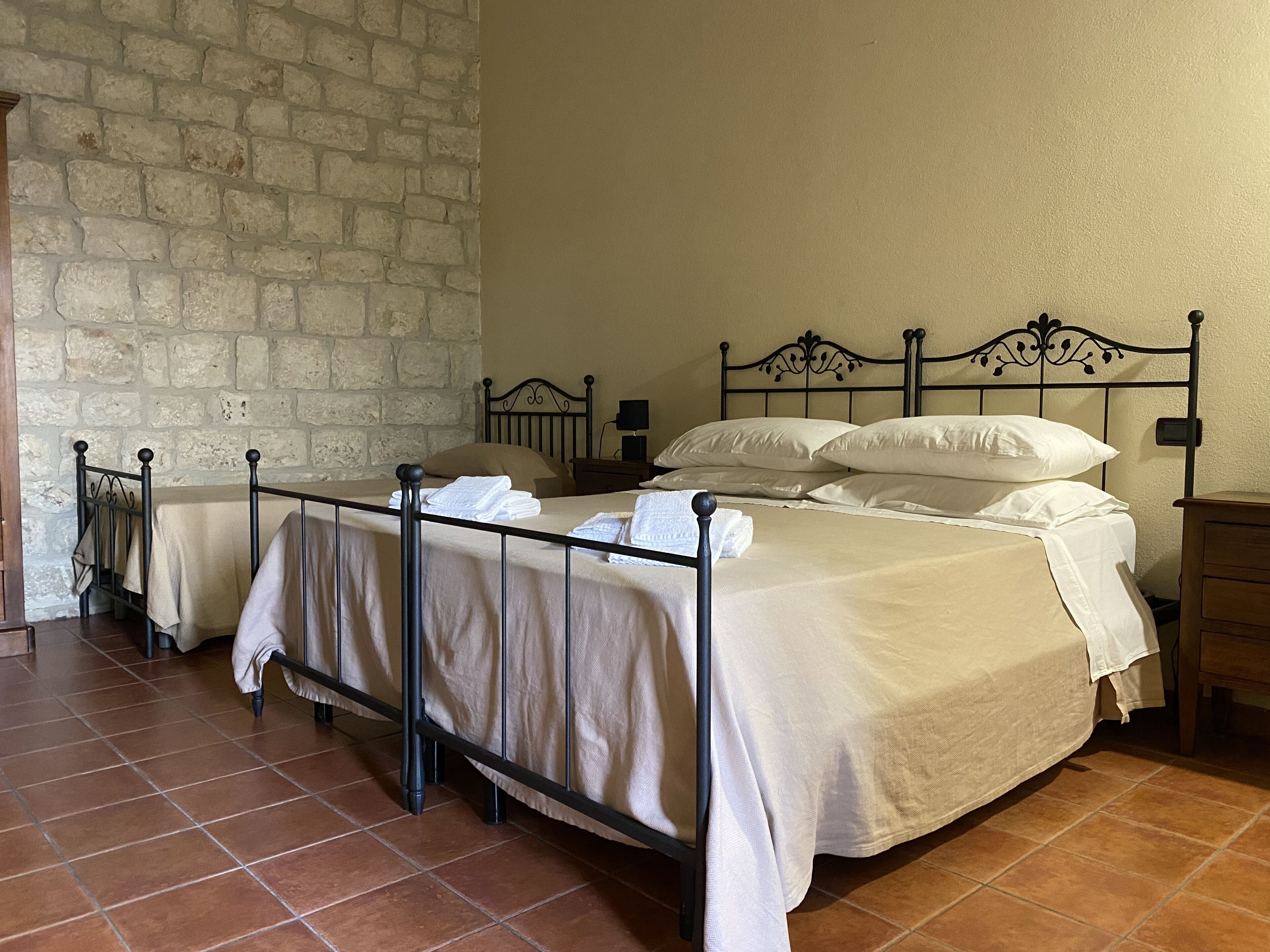 Una habitación con dos camas, pared de ladrillo y suelo de baldosas.