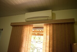 Una stanza con condizionatore a muro, una finestra con un motivo geometrico e una tenda.