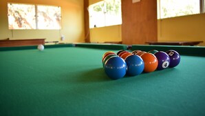 Une table de billard recouverte d’un drap vert, avec une bille blanche et un triangle contenant les billes numérotées.