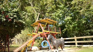 Une aire de jeux avec un toboggan, une structure d’escalade et une statue de cheval.