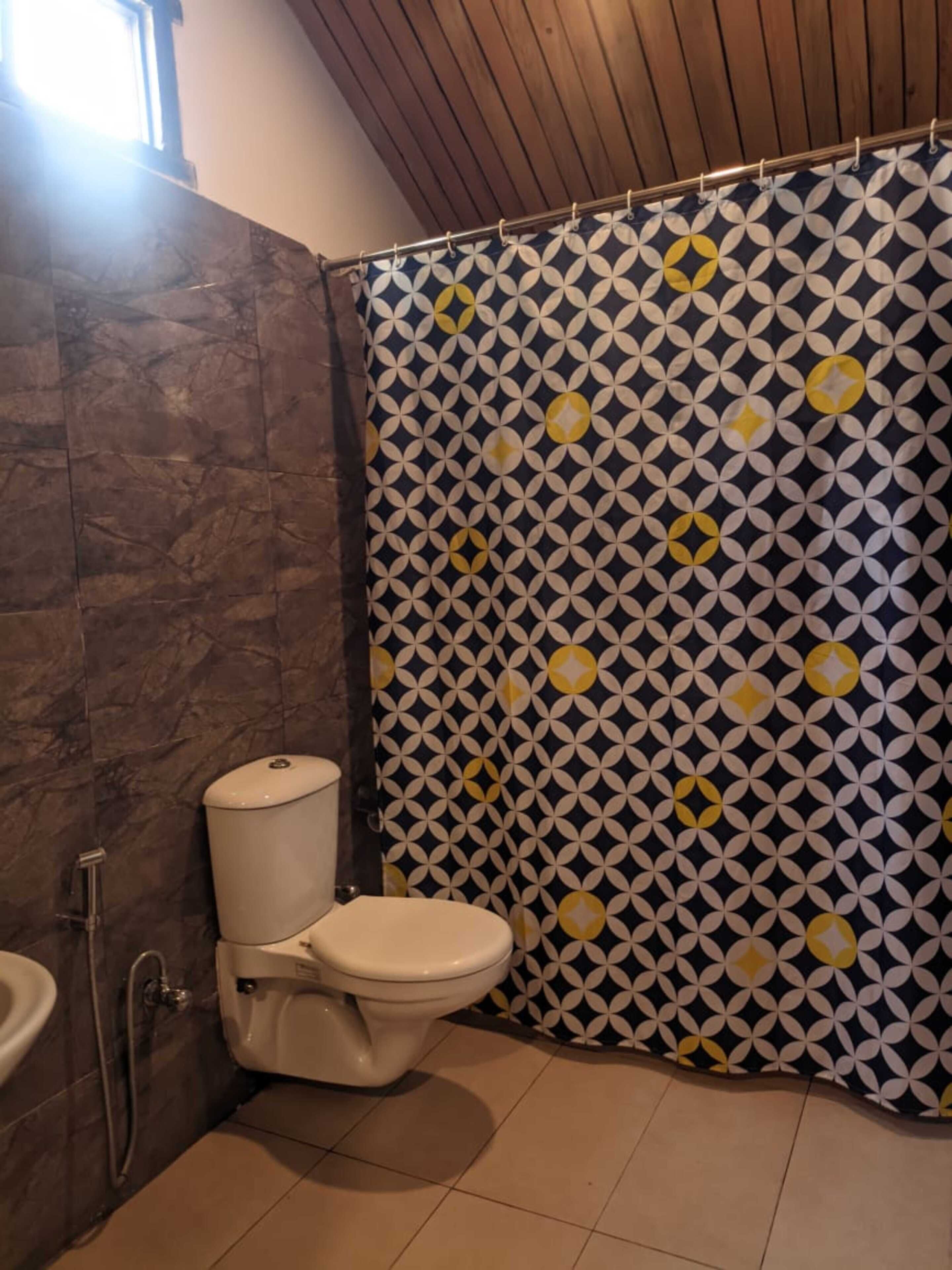 Un bagno con servizi igienici, tenda doccia e pareti piastrellate.