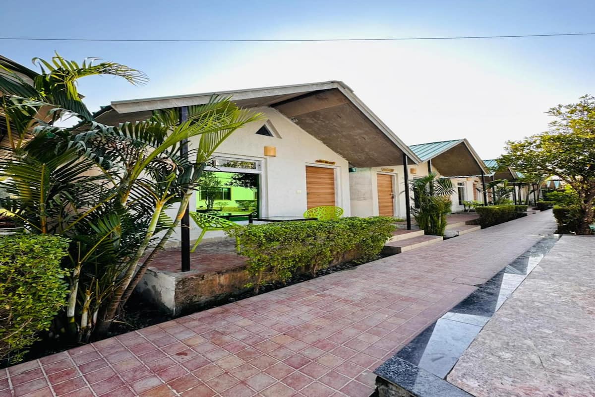 Um hotel moderno com galeria coberta, palmeiras e área de estar ao ar livre com vegetação.