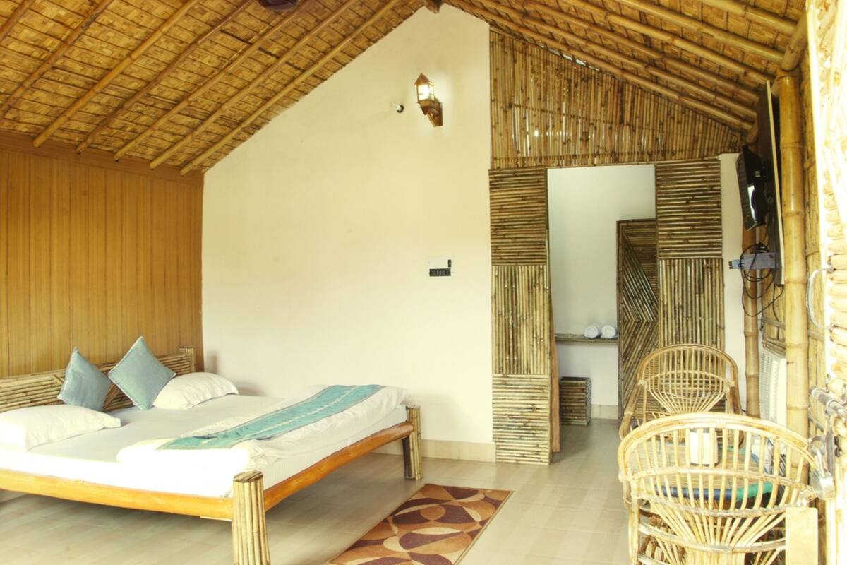 Quarto com cama, cadeira e teto de bambu.