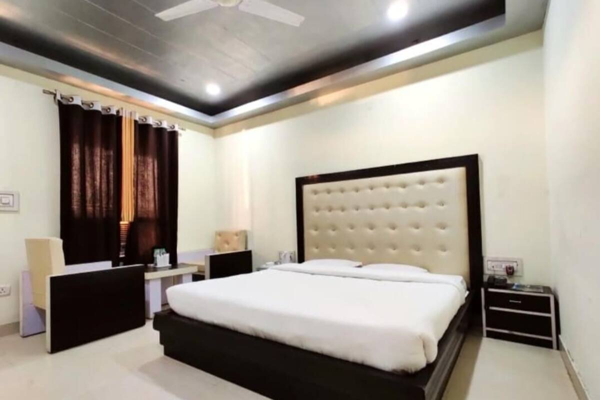 Quarto moderno com uma cama grande, mesas de cabeceira, ventilador de teto e um criado-mudo.