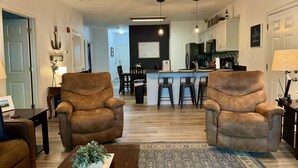 A living room with two brown armchairs, a coffee table with a plant, and a kitchen in the background. - Lake Vacation Condo A-5 on Table Rock Lake by RedAwning (Hollister)