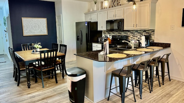 A modern kitchen with white cabinets, a black refrigerator, and a granite countertop. - Lake Vacation Condo A-5 on Table Rock Lake by RedAwning (Hollister)