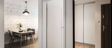 Un interior moderno con comedor, una puerta blanca y piso de madera.