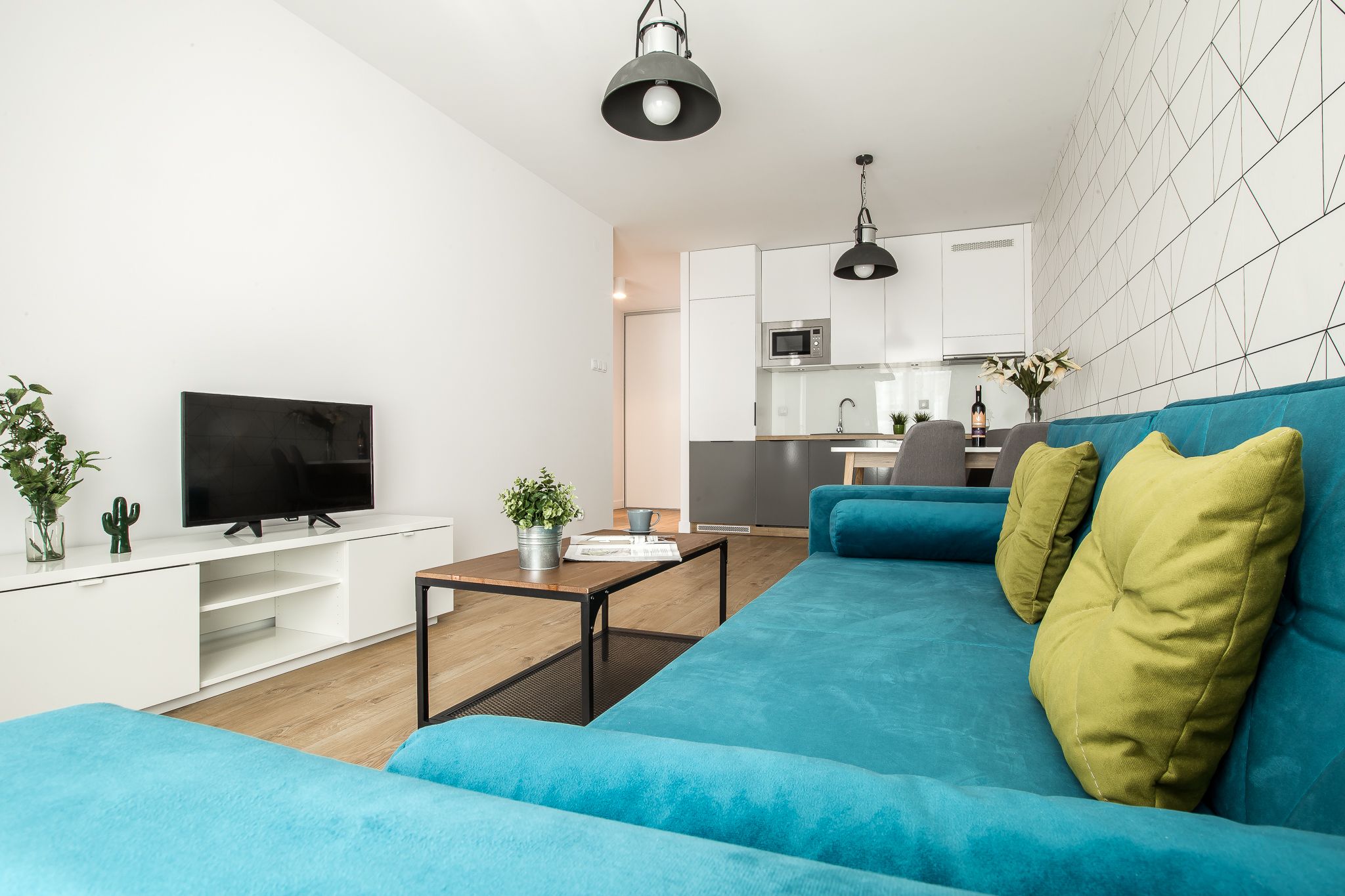 A modern living room with a blue sofa, a flat-screen TV, and a small coffee table.