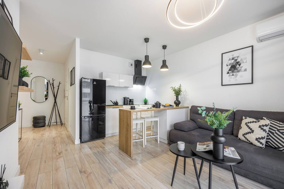 A modern kitchen with a built-in refrigerator, a dining area with a white table and chairs, and a living room with a sofa and a coffee table.