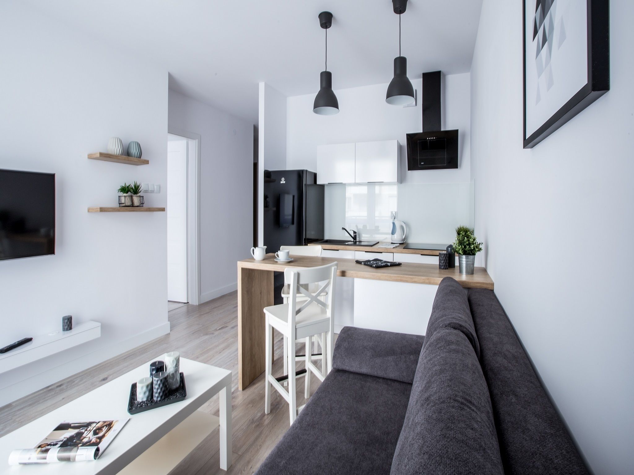 A modern living room with a grey sofa, a white coffee table, and a TV on the wall.