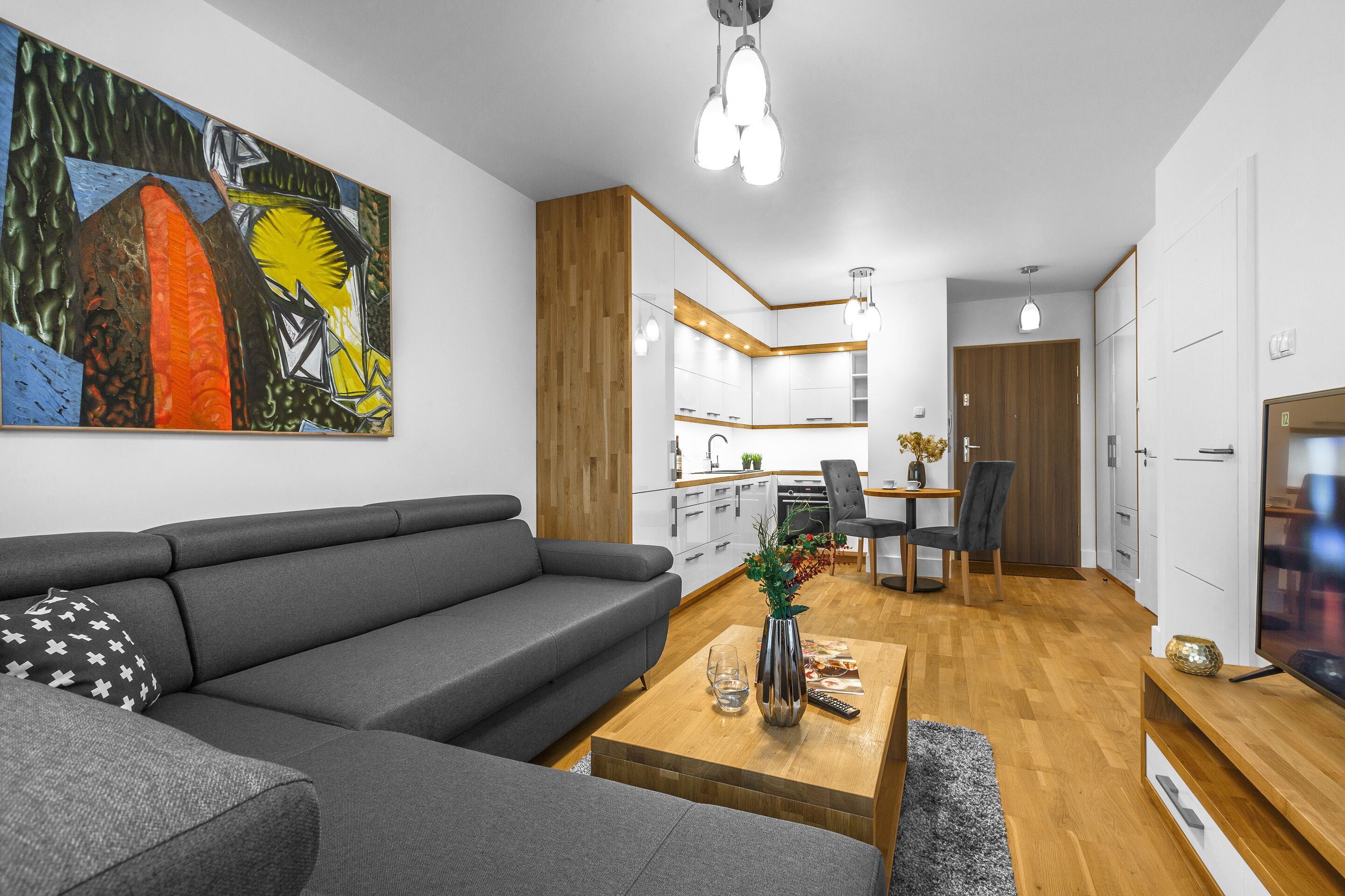 A modern living room with a gray sofa, wooden coffee table, and a painting on the wall.