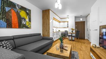 A modern living room with a gray sofa, wooden coffee table, and a painting on the wall.