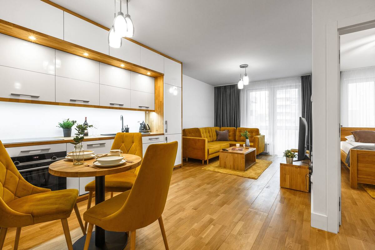 A modern living room with a sofa, coffee table, and dining area with chairs.