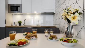 A breakfast setup with various dishes, a microwave, and a vase with flowers.