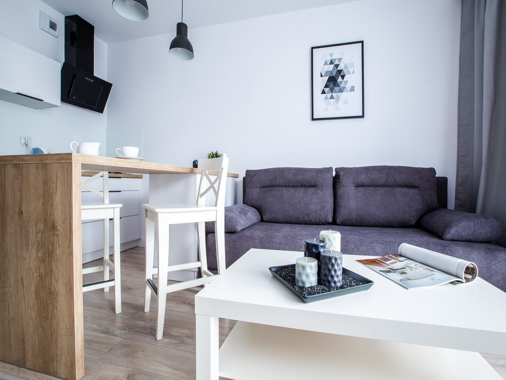 A modern living space with a kitchen area, a dining table, and a sofa.