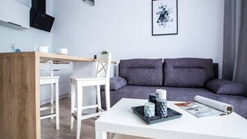 A modern living space with a kitchen area, a dining table, and a sofa.
