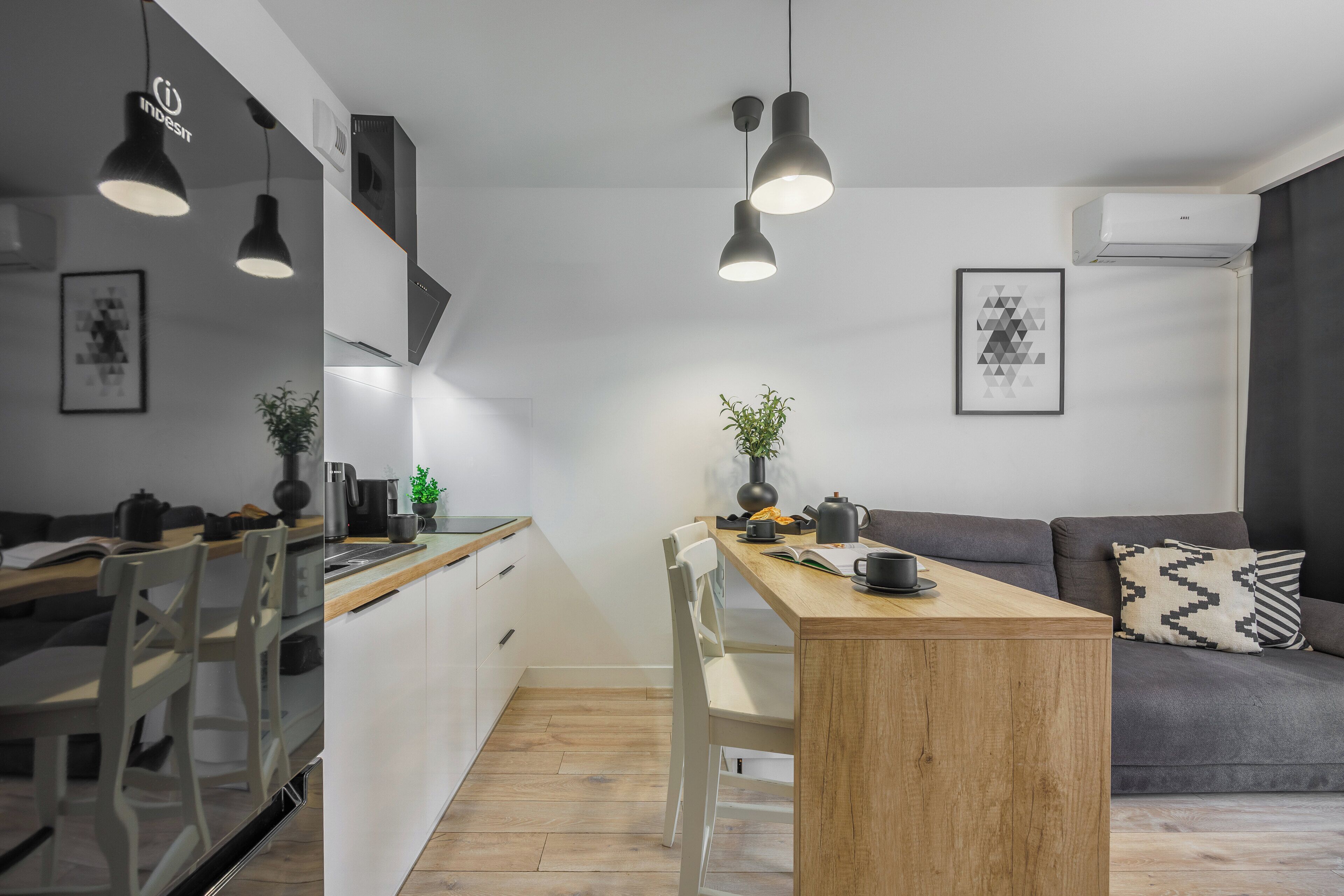 Una cocina moderna con armarios blancos, una mesa de comedor de madera e iluminación colgante.