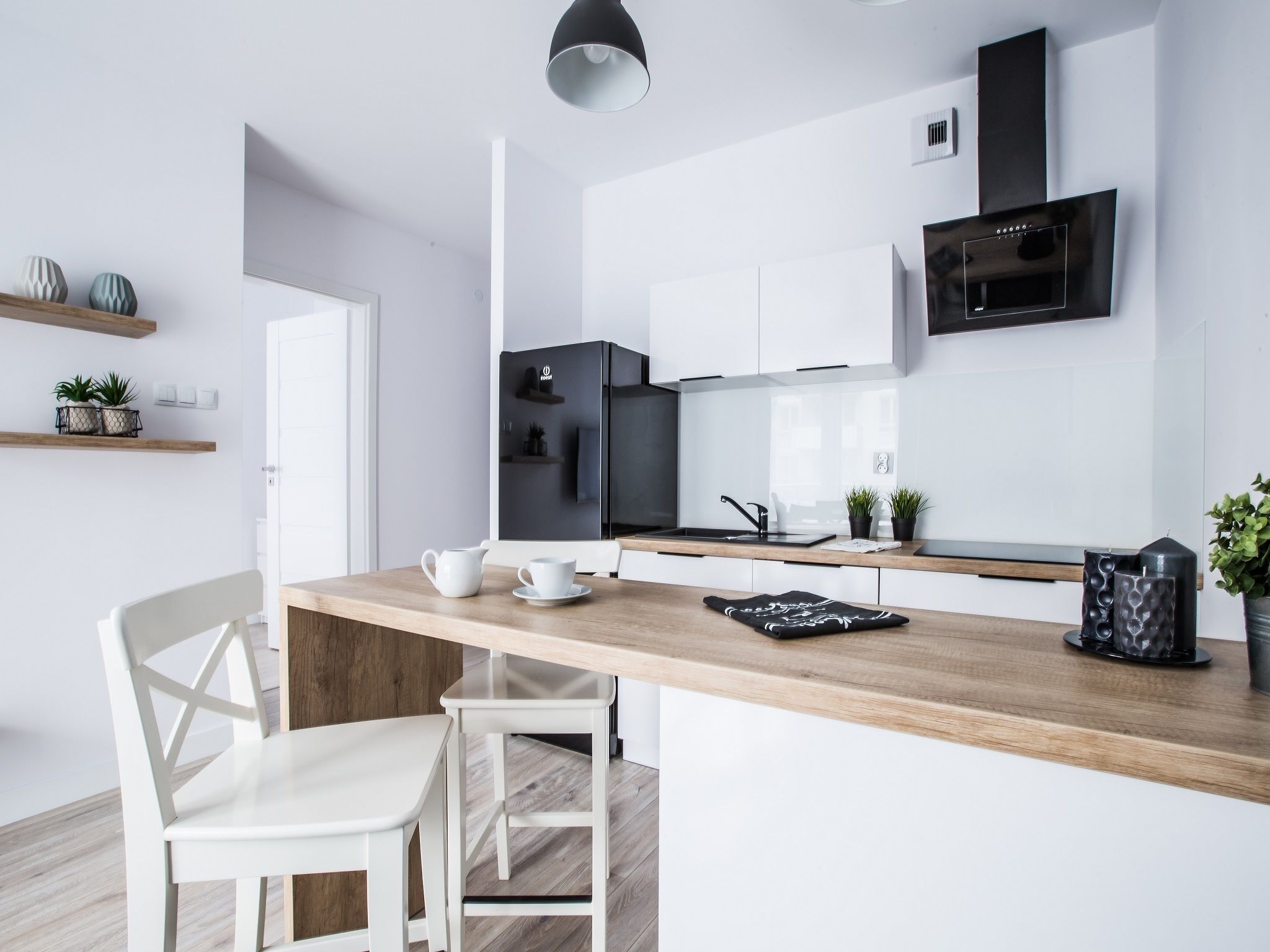 A modern kitchen with white cabinetry, a black refrigerator, and a wooden countertop.