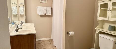 A bathroom with a sink, mirror, towel rack, shower curtain, toilet, and cabinet.