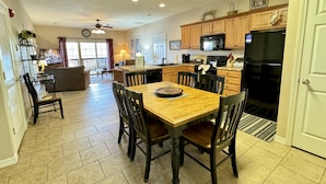 A spacious kitchen with wooden cabinets, a dining table, and chairs. - Walk-in Condo A-4 with Overlooking Deck by RedAwning (Hollister)
