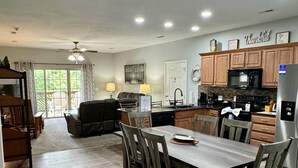 A spacious kitchen with wooden cabinets, a dining area with a table and chairs, and a view of the outdoors through large windows.