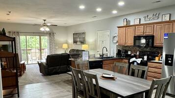 A spacious kitchen with wooden cabinets, a dining area with a table and chairs, and a view of the outdoors through large windows.