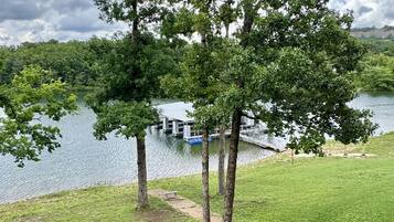 A grassy area with trees and a lake view.